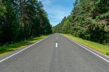 Fototapeta na wymiar Empty asphalt road close-up against the background of the forest. Empty background, space for text. New asphalt concrete pavement in rural areas.
