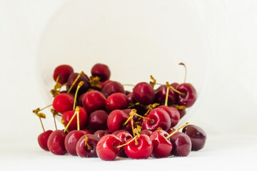 Red cherries on a white fabric background. Many sweet cherries closeup. Juicy organic red cherries for jam, juice, smoothies, compote, desserts and cakes. Healthy eating and food concept