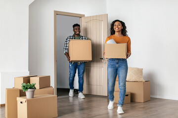 Fototapeta na wymiar Cheerful Black Couple Entering New House Carrying Moving Boxes Indoor