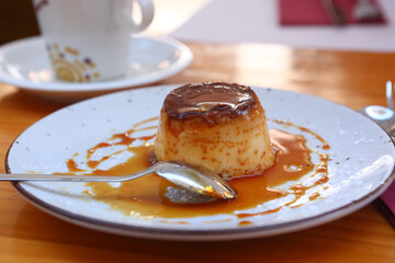  spanish flun pudding dessert close up photo with teaspoon and cup of coffee on the background