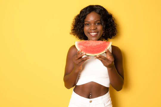 Photo of excited dark skin girl bite natural watermelon slice wear white t-shirt isolated on yellow color background