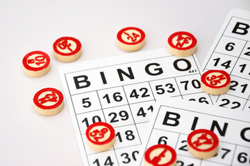 Many wooden chips with numbers and cards for a board game of bingo or lotto on a light background.