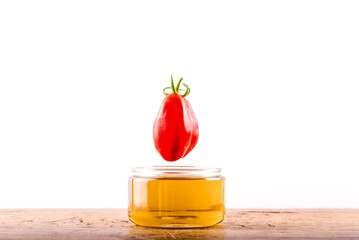 Olive oil in the glass and one red tomato
