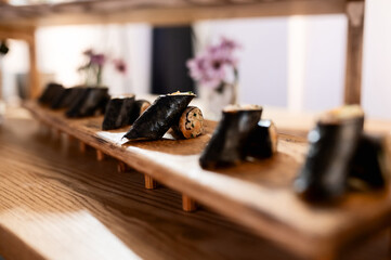 lots of black sushi with cucumber and fish