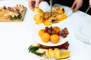 Fresh fruits in platdifferent fresh fruits on a white plate on a wooden tablee with cutting board on wooden table