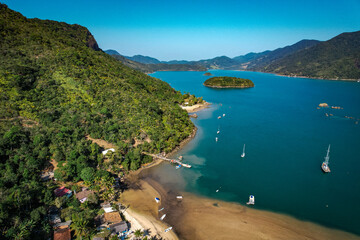 Fototapeta premium A lagoon with blue water and yachts, with a tropical forest, aerial view