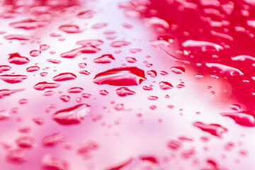 Drops of water on a red metal surface.