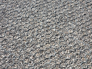 Texture of gray pebble in a geogrid. Grey stony floor. A wall of gray gravel. Stones small and medium-sized.