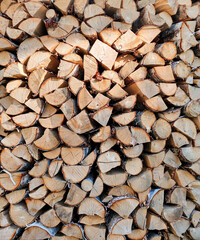 A stack of firewood, log ends, chopped birch and pine firewood. Vertical texture