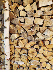 A stack of firewood, log ends, chopped birch and pine firewood. Vertical texture