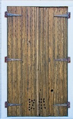 Weathered wooden plank window shutters with small holes