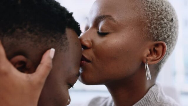 Love, trust and support of black couple with wife kissing head of husband for affection and bonding at home. Married african man and woman being close and sharing romantic moment while feeling secure