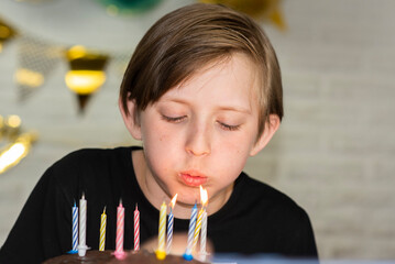 portrait of a little boy blowing out candles on a cake