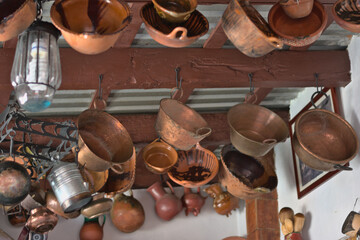 Copper and clay pots hanging from the ceiling of a kitchen