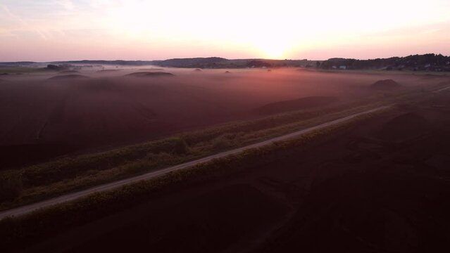 Peat extraction site in fog on sunset. Collecting peat on peatlands. Mining and harvesting peatland. Area drained of the mire are used for peat extraction. Drainage and destruction of peat bogs.