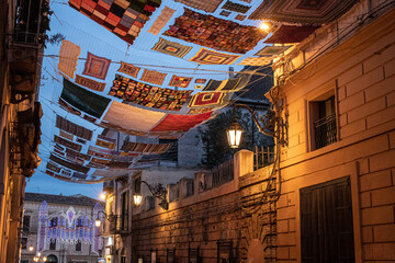 Large colored crochet cloth suspended between the buildings of the city of Rossano in Calabria.