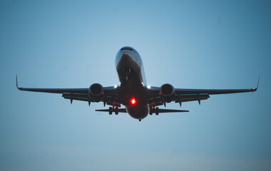 The silhouette of a passenger plane coming in for landing against the backdrop of the sunset sky.