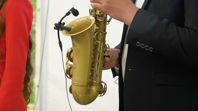 Concert view of saxophonist, a saxophone sax player with vocalist and musical band during jazz orchestra show performing music on stage in the scene lights