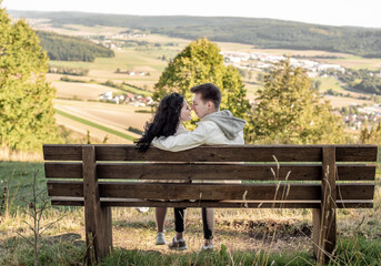 A couple in love, a guy and a girl sit on a bench and caress each other, kiss