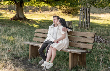 A couple in love, a guy and a girl sit on a bench and caress each other, kiss
