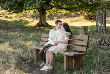 Fototapeta premium A couple in love, a guy and a girl sit on a bench and caress each other, kiss