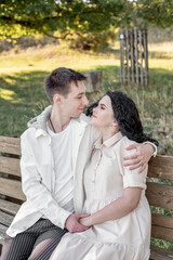 Naklejka premium A couple in love, a guy and a girl sit on a bench and caress each other, kiss