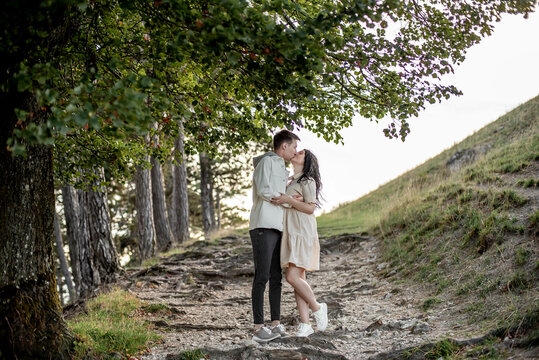 A couple in love, a guy and a girl are standing in the forest and kissing