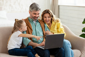 Parents And Little Daughter Using Laptop Computer At Home