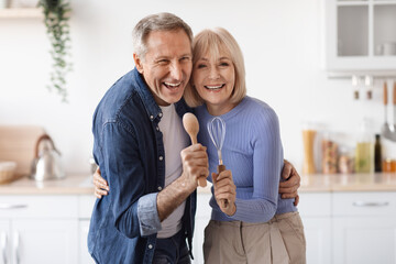Loving senior couple enjoying time together in kitchen, singing