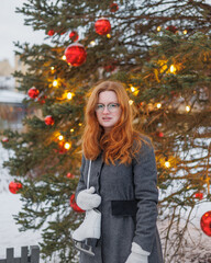 woman is resting and walking in the park in winter, a happy European woman with red hair is skating. a young and beautiful woman in a gray vintage coat is enjoying the Christmas holidays