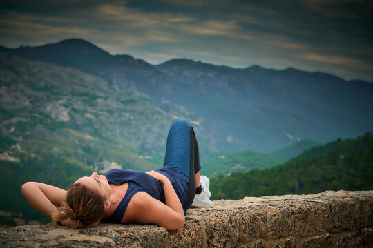 chica tumbada sobre roca en la naturaleza mirando el cielo