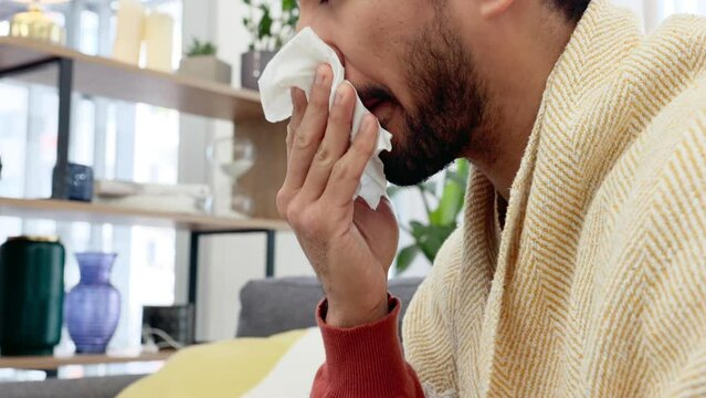 Covid, health and home, a man sick in living room with flu or cold symptoms. Healthcare, medicine and work leave for recovery from virus. A sneeze, tissue and a weak immune system, home in pandemic.