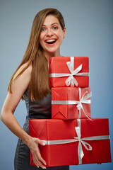 Happy woman in business dress holding stack of red gift boxes. isolated female studio portrait.