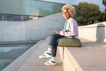 Modern African American professional female sitting on urban staircase after work