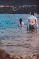 A couple standing in the sea with their backs turned. High quality photo