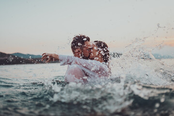 Romantic couple kissing in the sea at sunset. High quality photo