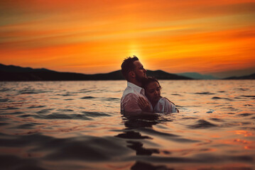 Romantic couple kissing in the sea at sunset. High quality photo