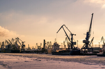 Fototapeta na wymiar Barges, cranes, ships for the transport of heavy goods, iron ore, sand in the river cargo port in winter. Docks in st. petersburg
