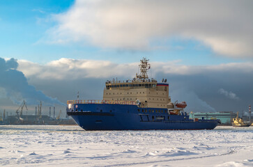 Diesel-electric icebreaker on a frozen river. Winter navigation in the port. Winter seascape at sunset.