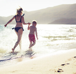 happy family mother and son have a fan on the sea beach in sunset light