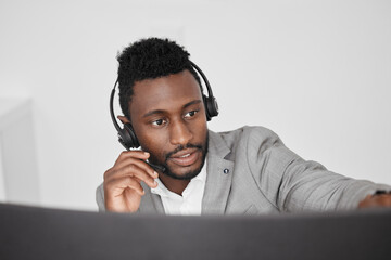 Call center, customer service and crm representative wearing headset while consulting with customer in telemarketing company. Serious black man in contact us and sales support working on a computer - obrazy, fototapety, plakaty