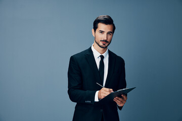 Portrait of a business man in a stylish suit smile with tie beautiful face on a blue isolated background with a tablet in his hands. Business concept young businessman startup copy place