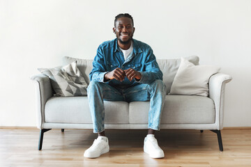 Successful Black Millennial Male Sitting On Couch Indoor