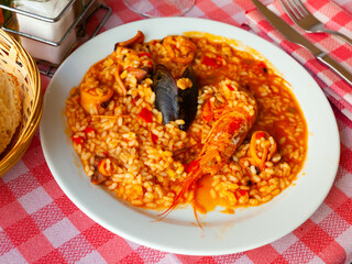 Traditional seafood paella with mussels, calamari and shrimps on white plate