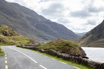 Scenic view of R335 road curving along Doo Lough lake with surrounding mountains in County Mayo,...