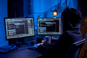 cybercrime, hacking and technology concept - female hacker in dark room writing code or using...