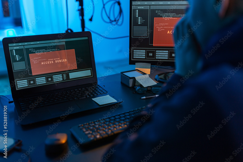 Poster cybercrime, hacking and technology concept - close up of male hacker in dark room using computer vir