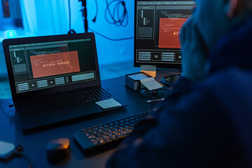 cybercrime, hacking and technology concept - close up of male hacker in dark room using computer...