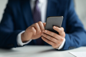 Cropped Shot Of Businessman In Suit Using Smartphone At Workplace