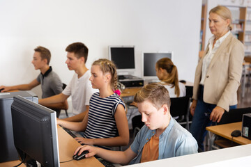 Obraz premium Group of teenage students working with computers in classroom